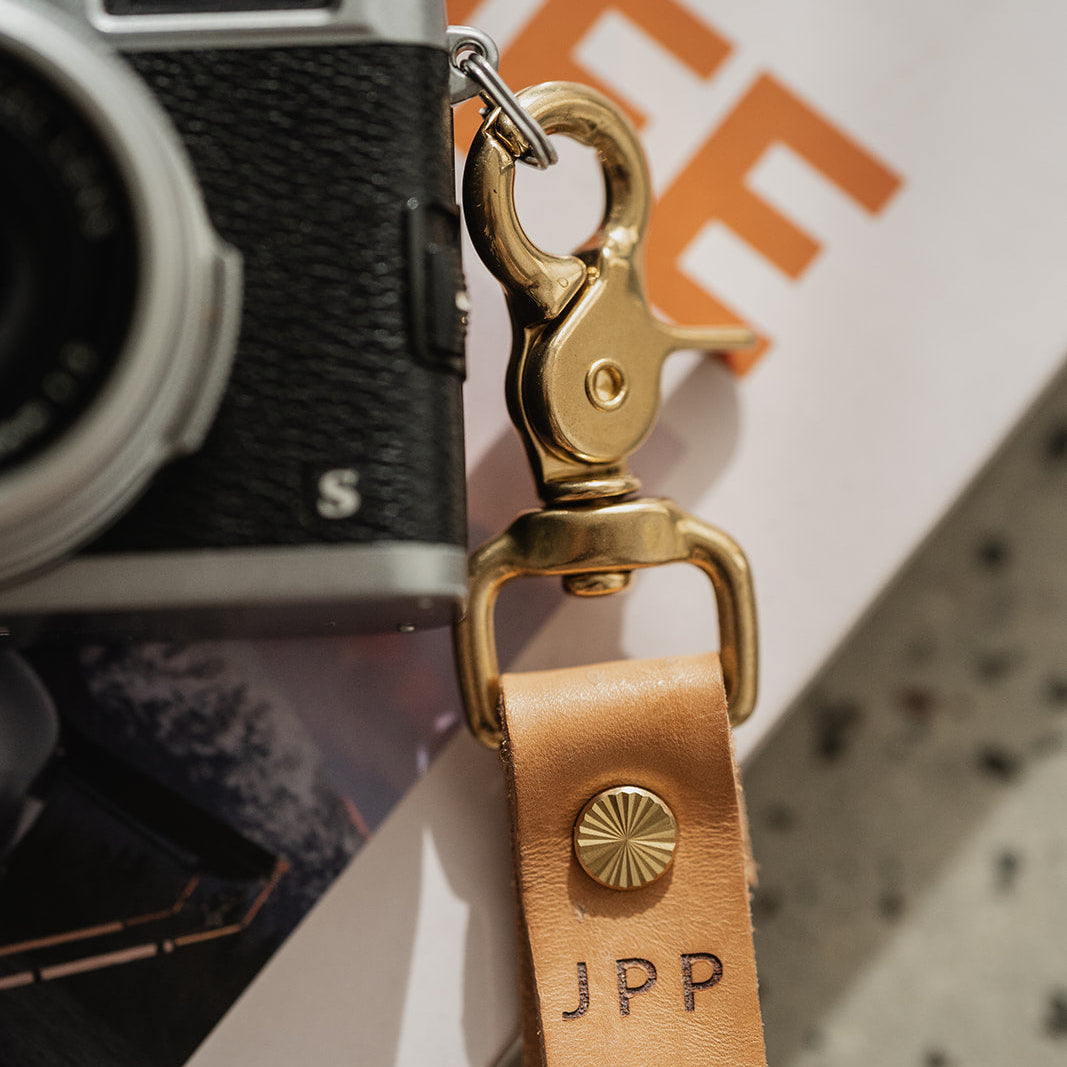 Vintage camera with a leather strap featuring 'JPP' on a blurred background