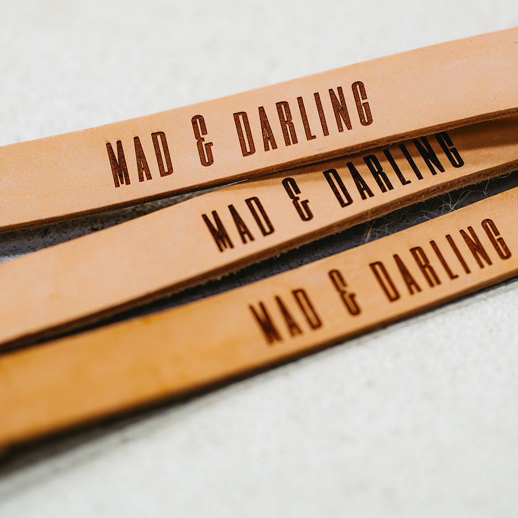 Three leather straps with 'MAD & DARLING' engraving on a light background