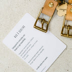 Gold and leather keychain with 'FRANK' tag on a beige background
