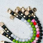 Colorful beaded bracelets with black leather straps on a light gray background