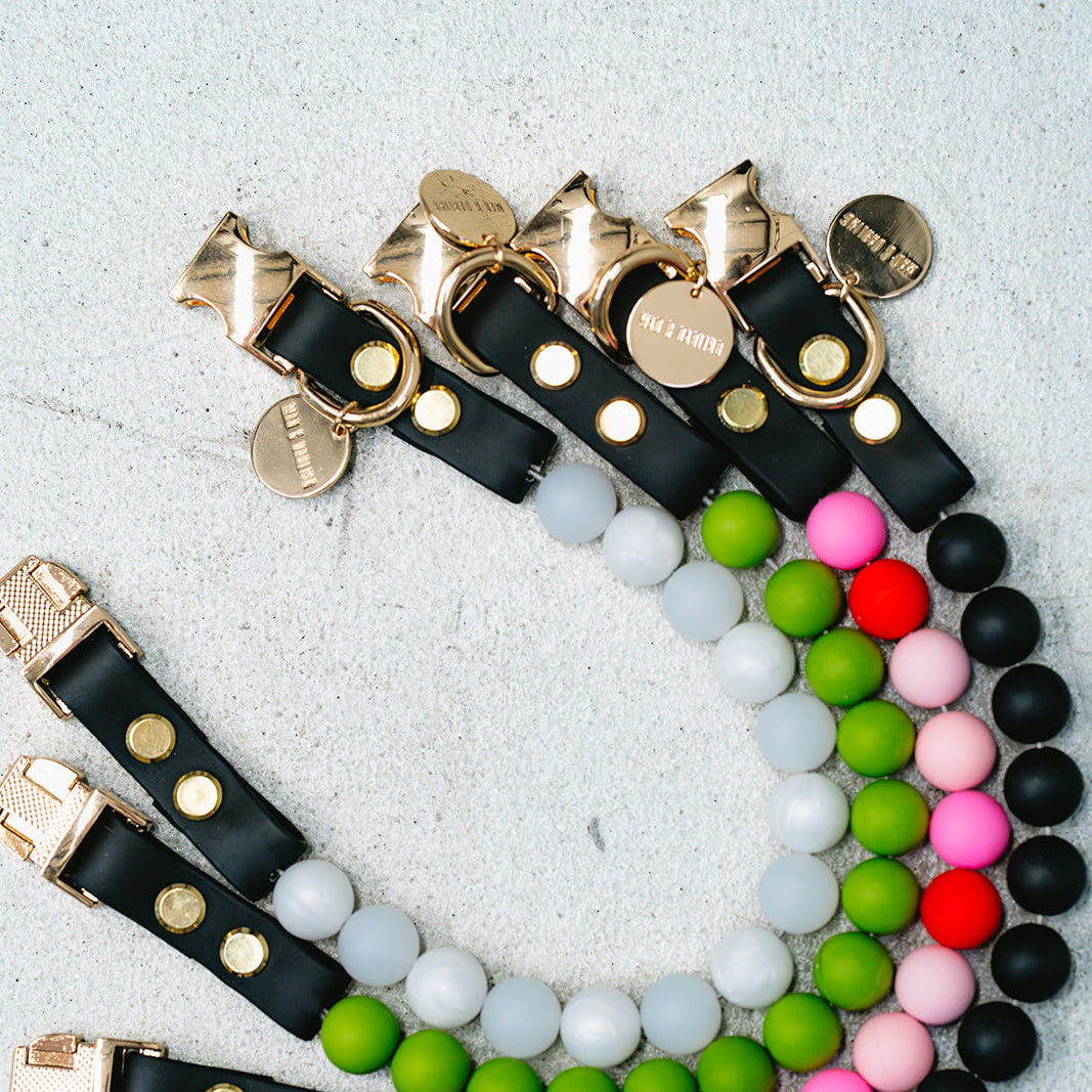 Colorful beaded bracelets with black leather straps on a light gray background