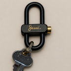 Keychain with a key attached to a black metal clip on a beige background