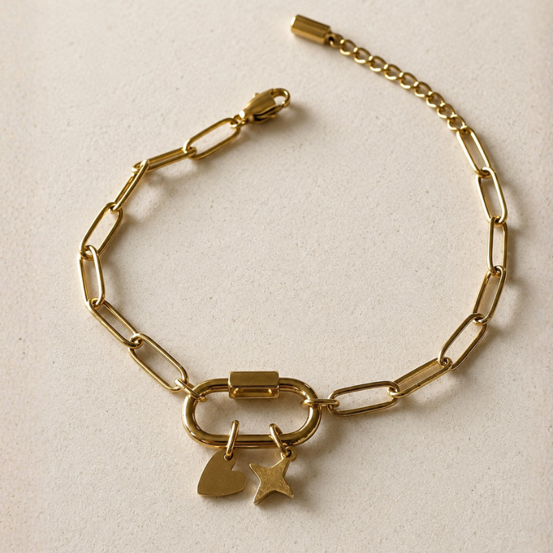 Gold chain bracelet with heart and star charms on a beige background